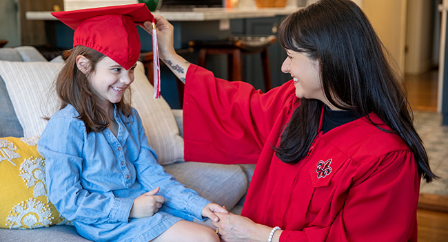 Student in graduation gown with daughter