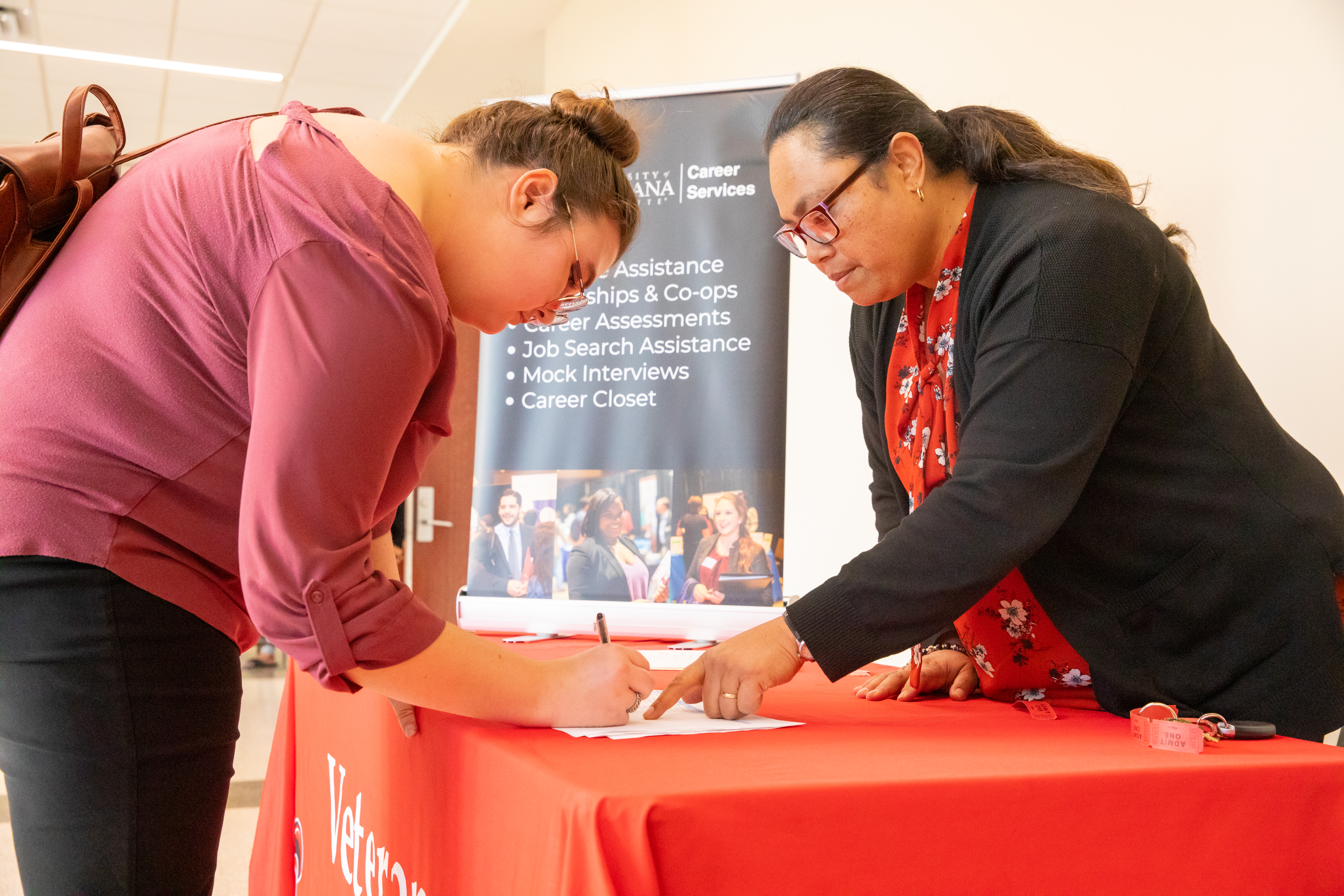 Special Services representative helps student fill out form at Career Services booth
