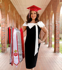 General studies online grad smiles on UL Lafayette campus, holding an array of stoles and honor cords on her arm.
