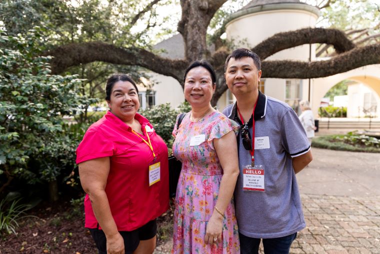 Three parents attending Orientation pose beneath an oak tree