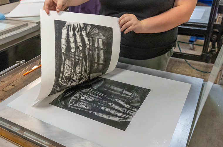 UL Lafayette printmaking student pulling their print off of their etching.