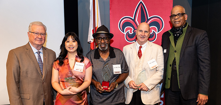 President Savoie and Dean Moore pose in front of a UL Lafayette College of the Arts banner at the annual SPARK award ceremony