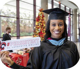 Online MEd graduate smiles holding a "#Persistent" UL Lafayette sign.
