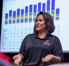 MBA in Finance online grad presents a financial report in a company meeting. 