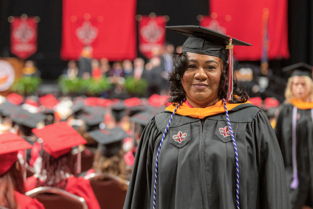 MSN online graduate smiles at Commencement, wearing her black UL Lafayette cap and gown.