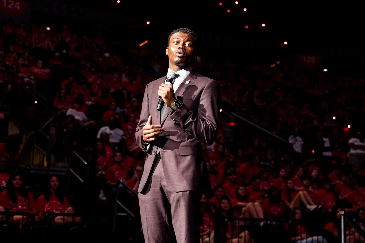 Student Tafari Beard stands on a stage with a microphone at new student convocation.