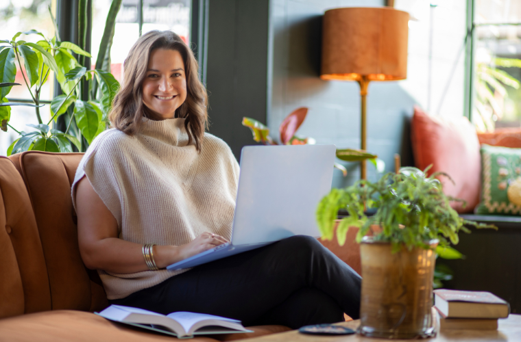Sales leadership online graduate smiles while working on a laptop. 