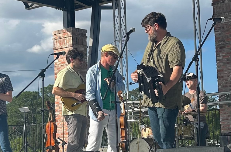 Three men stand on a stage a festival international