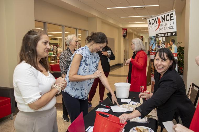Senior Instructional Designer Alise Hagan is pictured smiling as she welcomes FLC Showcase attendees at a registration table.