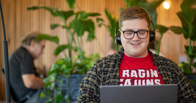 UL Lafayette online student smiles while working at laptop.