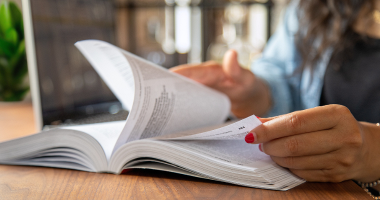 UL Lafayette online student flips through textbook while studying at a coffee shop.